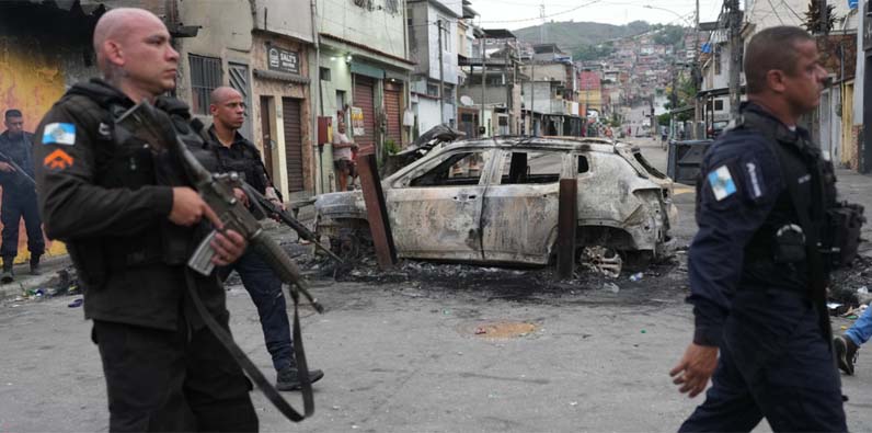 Policías junto a un coche quemado durante un operativo policial contra el Comando Vermelho en la favela Complexo do Alemao. Río de Janeiro, 28 de octubre de 2025.